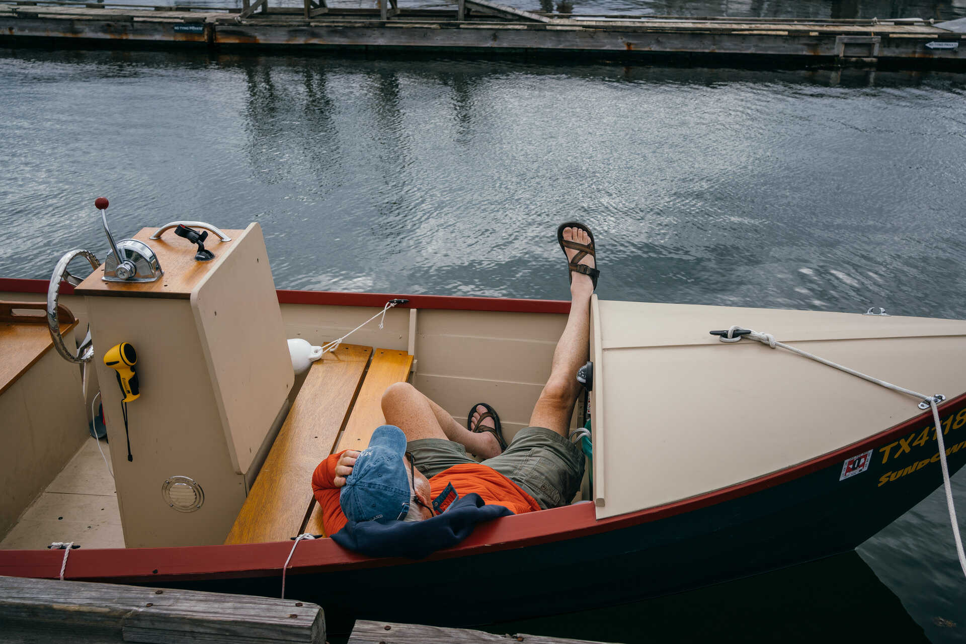 Man sleeping in a boat in BoothBay Harbor, Maine